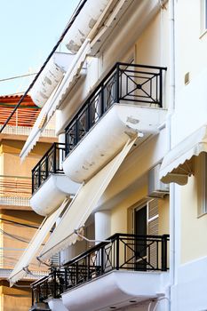 Fabric awnings on the balconies of buildings harmoniously combine with architecture and provide useful protection from harsh sunlight.