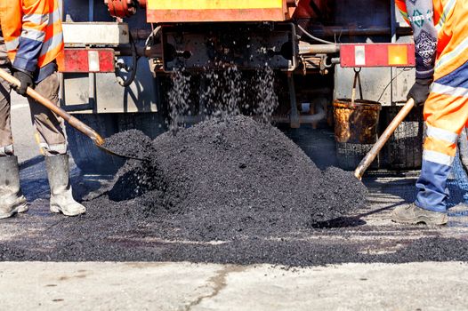 The road workers' team updates part of the road with fresh asphalt and levels it to repair a small section of the road.