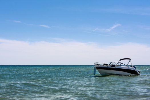 Vacation concept - empty white speed boat on seaside on blue sky background