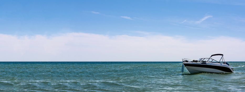 Marine vacation banner - empty white speed boat on seaside on blue sky background