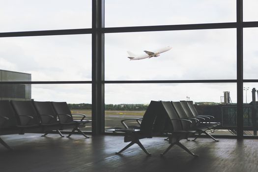 Traveling concept - empty interior of the airport lounge on the background of flying aircraft (vintage effect)