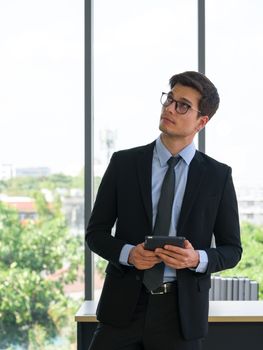 Business people in suits and ties look upward while thinking about the solutions of work while carrying tablet computers. Morning work atmosphere In a modern office.