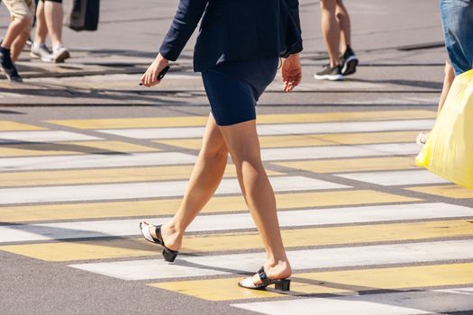 feet of pedestrians walking on the crosswalk on summer day