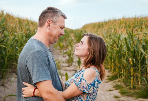 couple in love cuddling in a corn field on a summer day