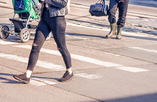 young woman feet, crossing an urban street on sunny spring day
 