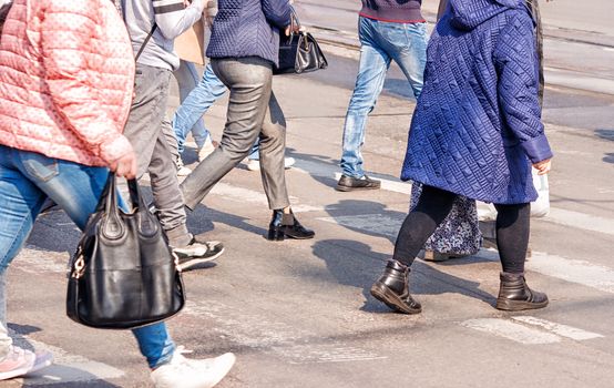 crossroad with walking pedestrians on sunny spring day