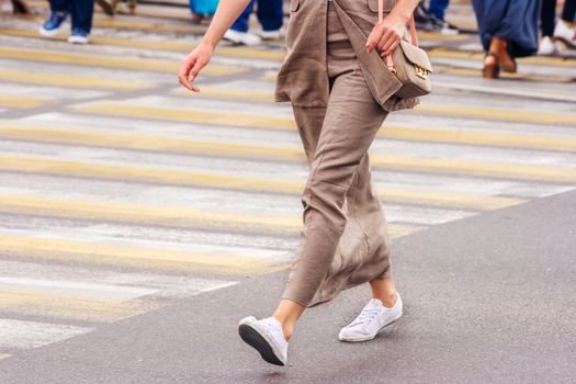 young woman feet, crossing an urban street on summer day