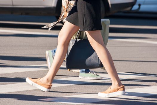 girl pedestrian walking on a crosswalk outside on sunny spring day