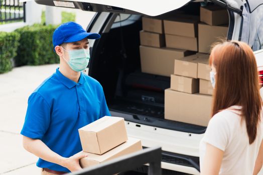 Asian young delivery man courier shopping online give parcel post box he protective face mask and service woman customer receiving boxed at front home door, under curfew pandemic coronavirus COVID-19