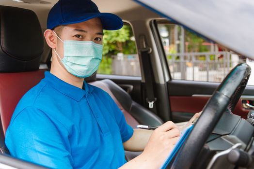 Asian delivery courier young man driver inside the van car with parcel post boxes checking amount he protective face mask, under curfew quarantine pandemic coronavirus COVID-19