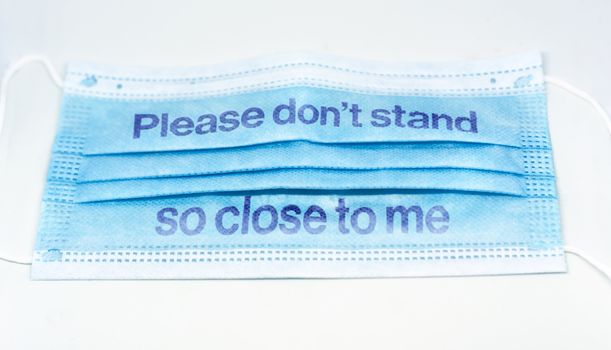 blue surgical mask with the indication to maintain social distancing and not to stay so close. Covid-19 pandemic and social distancing to prevent the spread of the virus