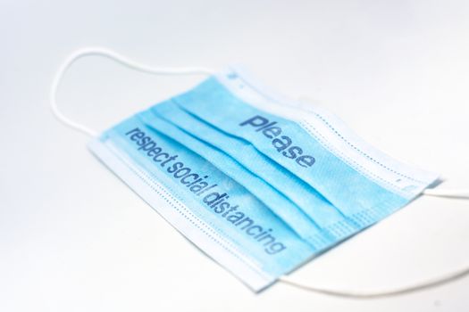 blue surgical mask with the indication to maintain social distancing and not to stay so close. Covid-19 pandemic and social distancing to prevent the spread of the virus