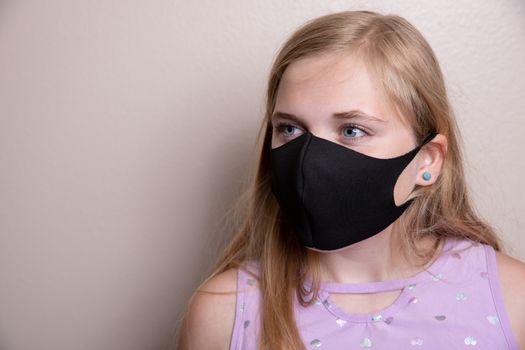 young girl trying to prevent the spread of disease by wearing a face mask