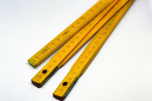 Yellow wooden folding meterstick with brass ends isolated on a white background. Fully extended it measures 2 meters. Measuring instrument used in construction industry
