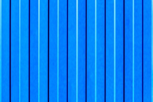 Light blue metallic fence made of corrugated steel sheet with vertical guides.