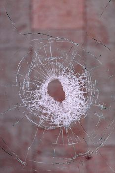 The bullet hole forms radial cracks in the glass against a blood-red background, vertical images with copy space.