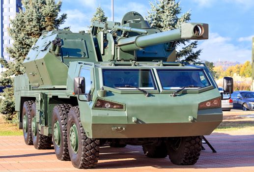 An army military vehicle with artillery anti-aircraft gun and guided missiles on board is parked in a car park on a bright summer day.