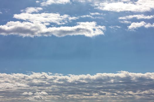 White and gray long clouds float high in the sky in the rays of beautiful back light covering the horizon, image with copy space.