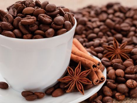 Grains of black coffee in a white porcelain dish. Cinnamon sticks and star anise on a white porcelain dish.