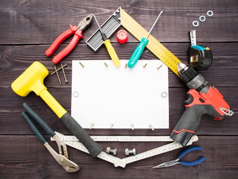 The tool building on the wooden background around the white sheet of paper