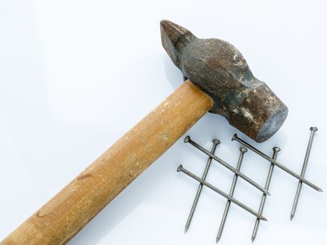 An old hammer with a wooden handle and a bunch of nails. Objects on a light background