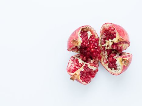 Ripe and red pomegranate fruits and divided into four parts, on a white background