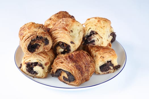 Sweet rolls with poppy seeds on a white porcelain plate with a blue rim and on a light blue surface