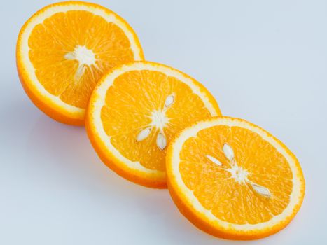 Three rings of sliced juicy ripe orange on a light blue background.