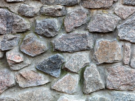 Seamless texture of a stone wall. Granite stone paving stone wall background. Abstract background of old stone cobblestone close-up.