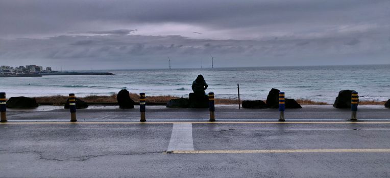 A woman overlooking the sea alone in Woljeongri beach in jeju island, south korea