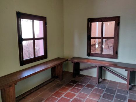 Two brown bench and two window soaking in the day sun