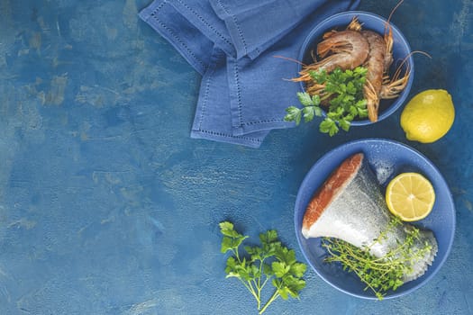 Trout fish surrounded parsley, lemon, shrimp, prawn in ceramic plate. Light classic blue concrete table surface. Healthy seafood background.