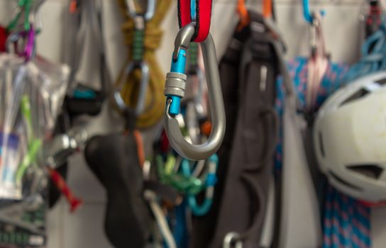 Screwgate carabiner attached to a nylon sling with a bunch of climbing gears on the background