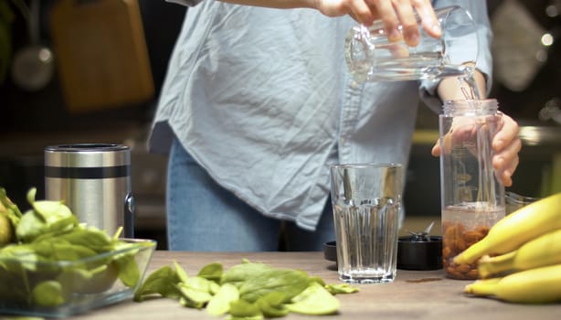 Cooking of almond milk. Woman pouring water into a blenders glass. Healthy lifestyle and eating concept