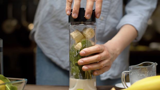 Close up female hands closing the blender glass with smoothie ingredients. Cooking smoothies in the kitchen. Healthy lifestyle and eating concept