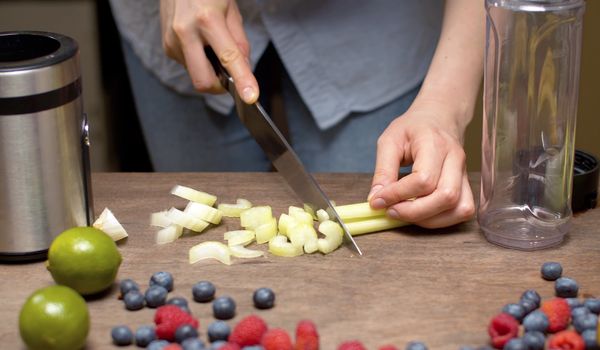 Close up female hands chopping celery. Cooking of smoothies closeup. Healthy lifestyle and eating concept