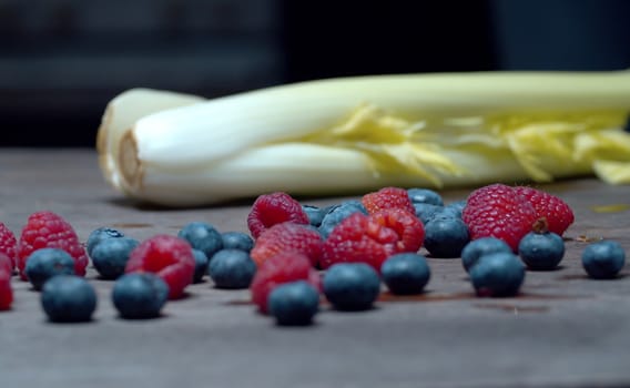 Celery, raspberries, blueberries on the wooden table closeup. Fruits and vegetables. Fresh healthy food