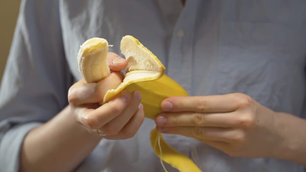 Close up female hands peeling a banana. Healthy lifestyle and eating concept