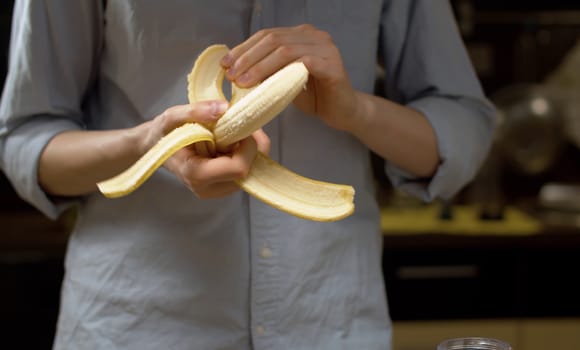 female hands peeling a banana. Healthy lifestyle and eating concept