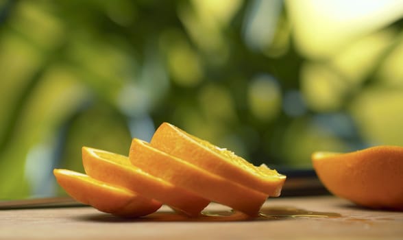 Close up sliced orange on the table over blurred natural background. Drops of juice on a table. Healthy eating concept.