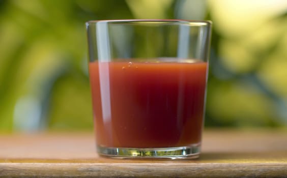 Glass of fresh tomato juice. Close up nutritious red beverage on natural background. Healthy lifestyle and vegetarian concept.