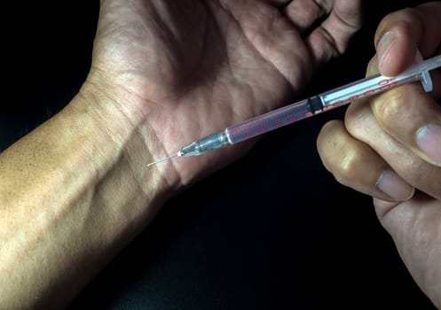 Man injecting with syringe to his hand