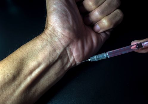 Man injecting with syringe to his hand