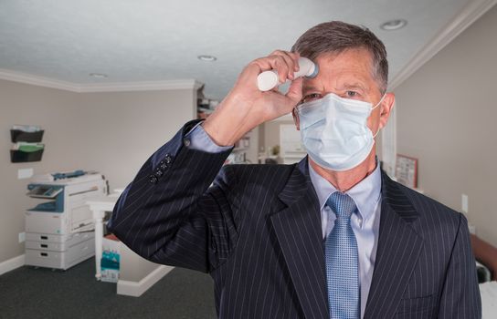 Mockup of senior adult wearing mask checking for a coronavirus fever with thermometer before going into office for meeting