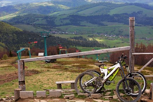 Carpathians. Two cyclists left mountain bikes for a respite. Ski lift in the background of a mountain landscape.