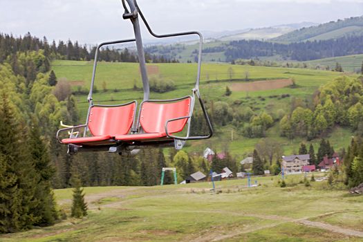 A pair of chairs of a mountain undercarriage hangs on a moving cable, which is used to transport passengers up and down the mountains.