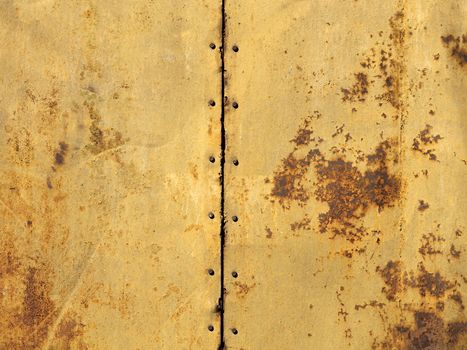Two old metal sheets with a rust texture are connected together by bolts