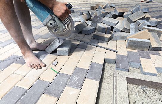 The worker cuts a bar of paving slabs for the final laying on the terrace