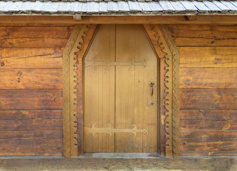 Ancient antique wooden doors of the old hut with wrought iron crossbar.