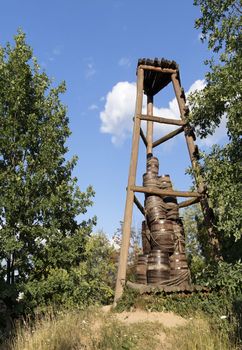 An old Cossack wooden watchtower on a hill in the middle of a forest that served as a signal and alert against a blue sky with a white cloud